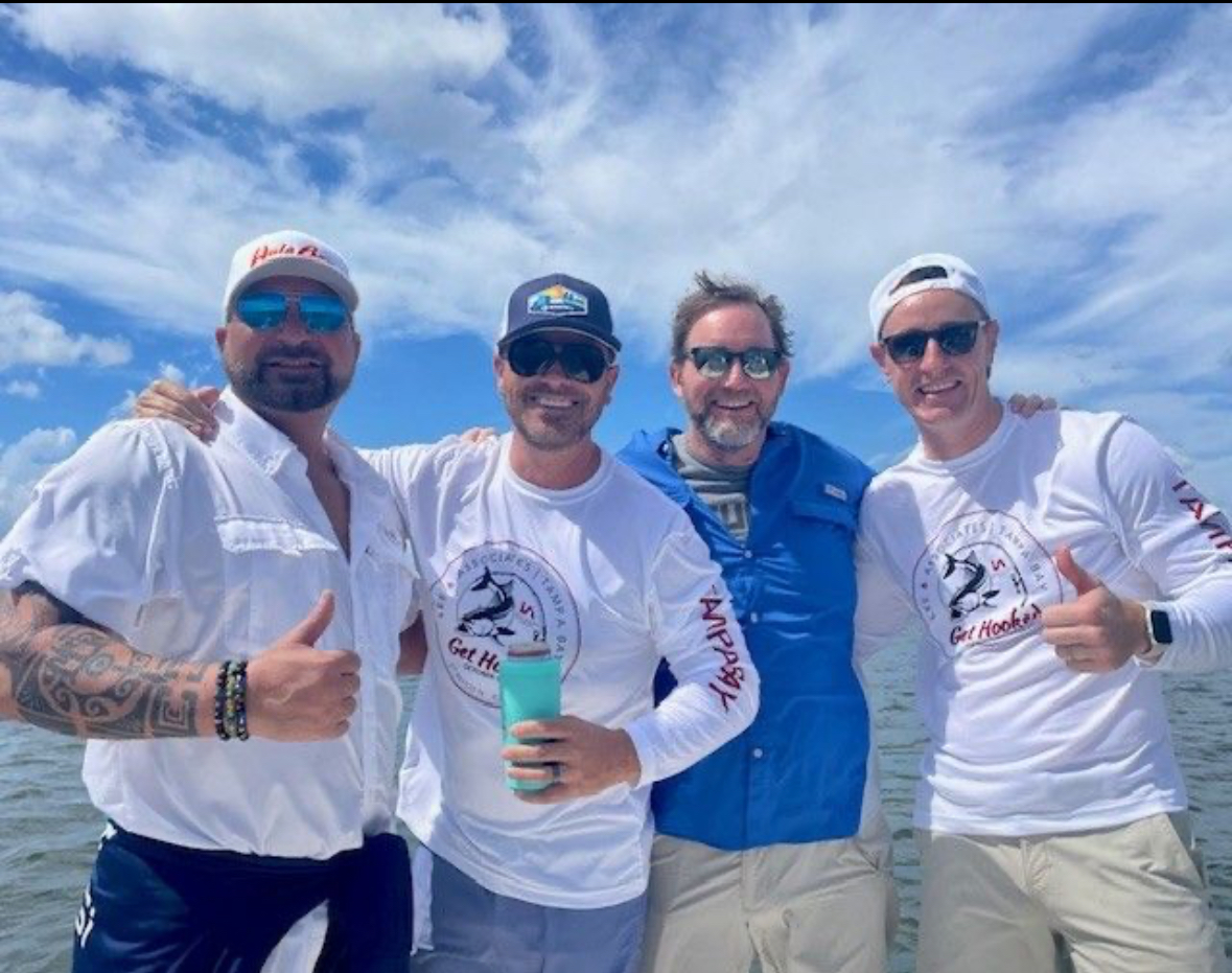 Four friends smiling on the boat in matching Get Hooked gear